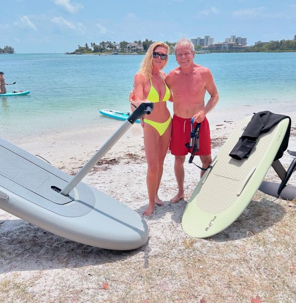 A man and woman posing together on the beach with a Flitescooter and Fliteboard